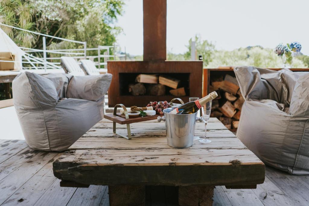 罗托鲁瓦Oakridge Glamping的庭院里的木桌和一瓶葡萄酒