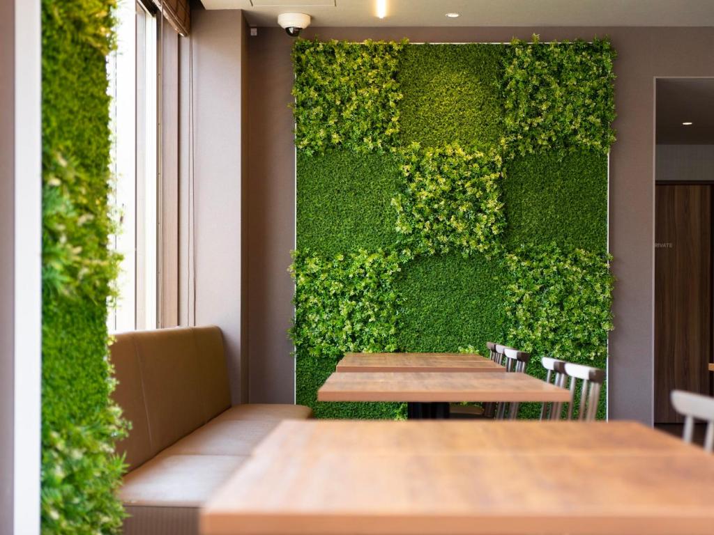泉佐野Super Hotel Kanku Kumatoriekimae的餐厅内带木桌的绿色墙壁