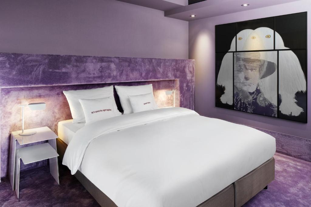 美因河畔法兰克福25小时高盛酒店的卧室配有白色的床和紫色墙壁