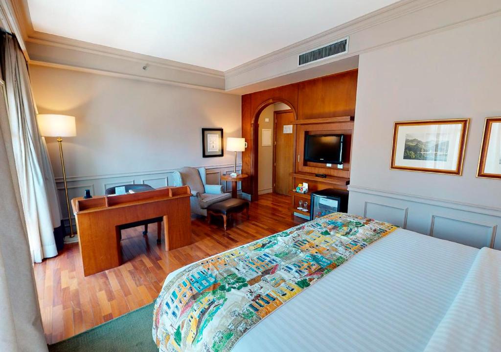 圣保罗博里尼埃斯坦广场酒店的一间卧室配有一张床和一张书桌,另一间卧室配有一张桌子。