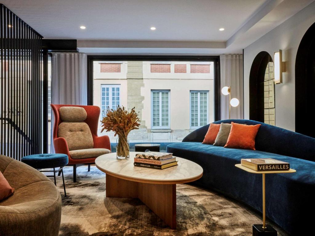 凡尔赛凡尔赛城堡美居酒店的客厅配有蓝色的沙发和桌子
