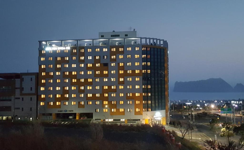 西归浦市Grandmillions Hotel Seogwipo的一座高大的建筑,晚上有很多窗户
