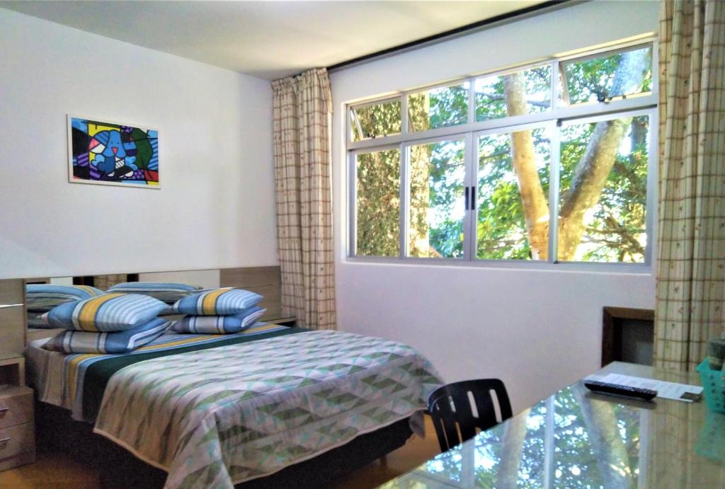 库里提巴Pousada Casa Verde - Curitiba的一间卧室设有一张床和一个大窗户