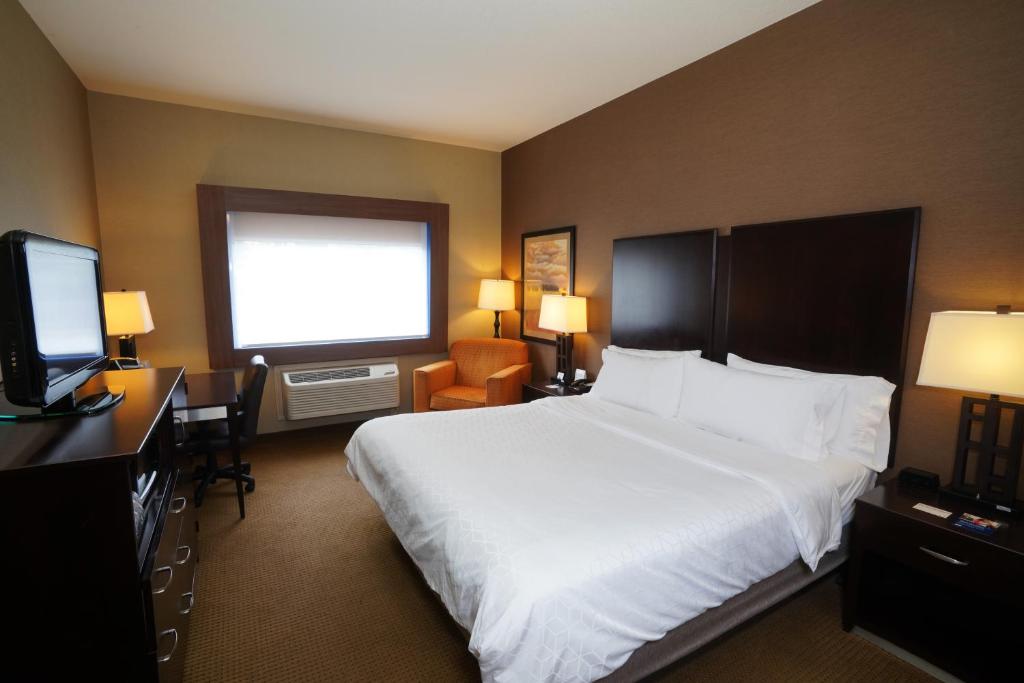 坎宁维尔Creekside Hotel & Suites的配有一张床和一台平面电视的酒店客房
