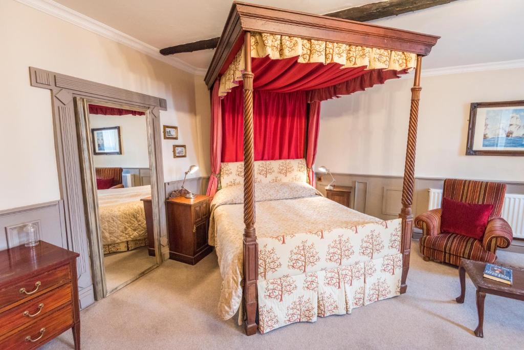 兰达弗里城堡酒店的一间卧室配有一张带红色窗帘的天蓬床