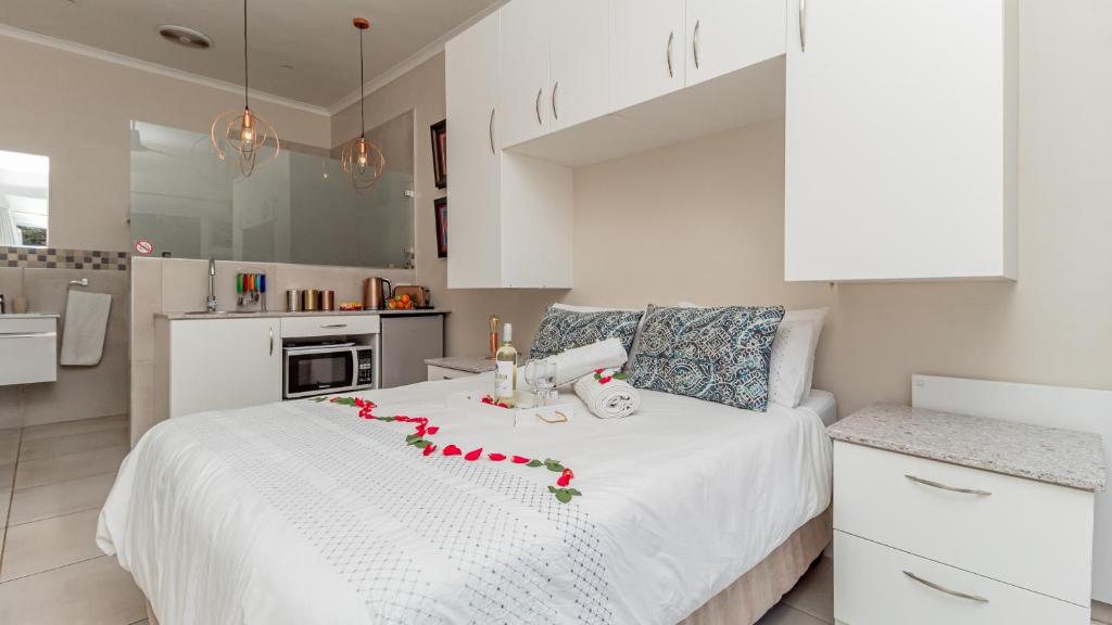 布鲁堡史特兰Sea Breeze的白色卧室,配有白色的床铺和红色的鲜花