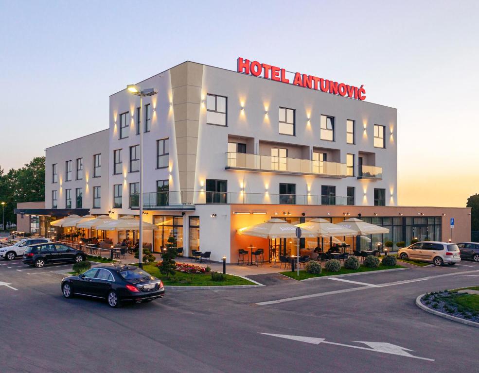 赛斯韦泰Antunović Hotel East的停车场内有车辆的旅馆
