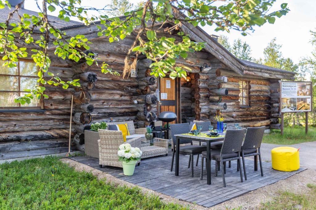 萨利色尔卡Kuukkeli Log Houses Teerenpesä - Superior Suite A49的小木屋前方设有带桌椅的天井。
