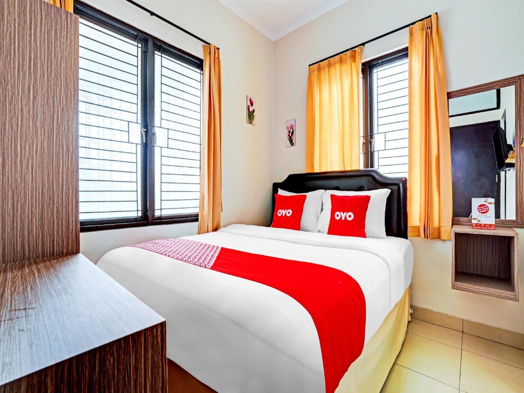 加拉旺OYO Life 90211 I-sidji Inn的一间卧室配有一张带红色枕头的大床