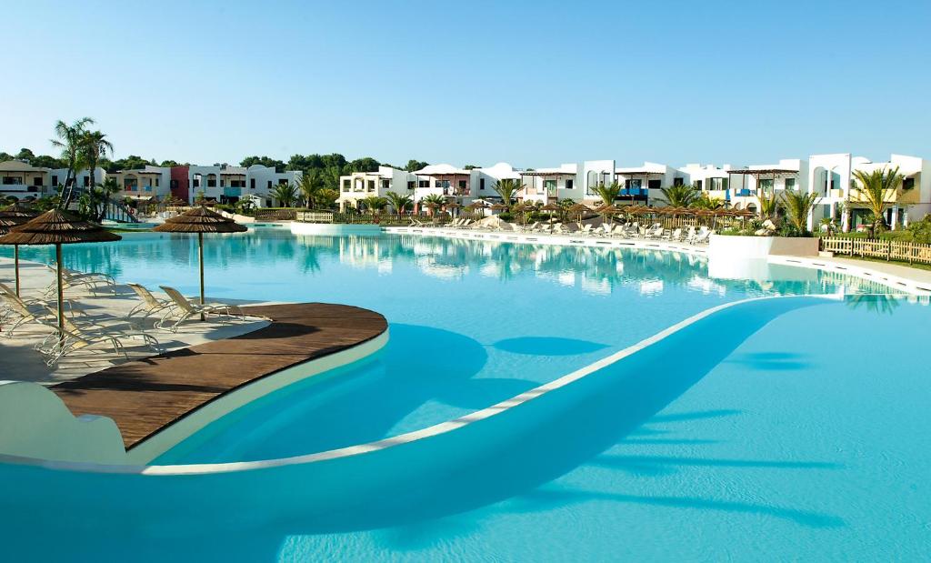 卡斯特拉巴特滨海爱图彻斯俱乐部村酒店的一个带椅子和公寓的大型蓝色游泳池