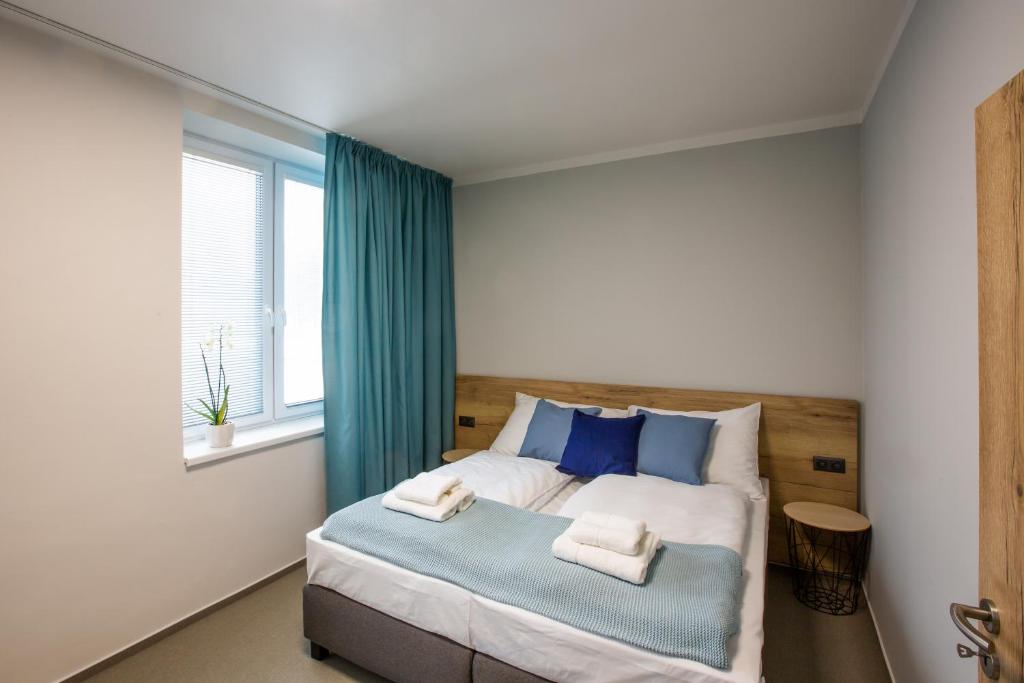 俄斯特拉发Penzion Start Ostrava的一间卧室配有一张带蓝色枕头的床和一扇窗户。