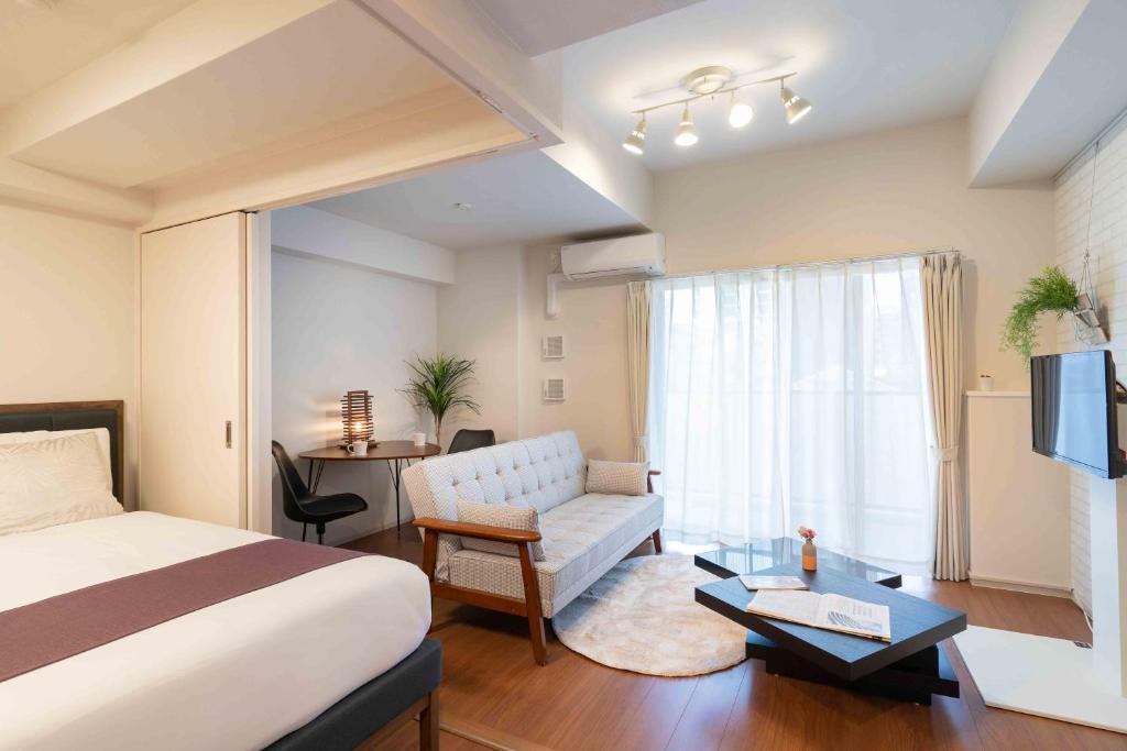 大阪BON Condominium Umeda的酒店客房设有床、沙发和窗户。