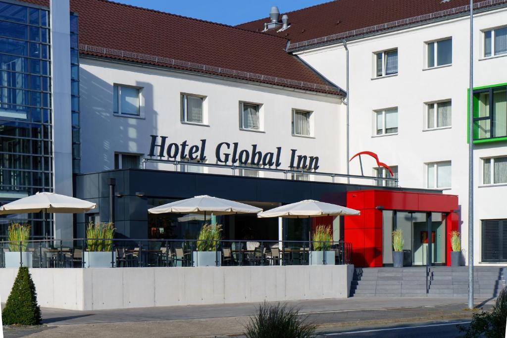 沃尔夫斯堡全球酒店的大楼前有桌子和遮阳伞的酒店