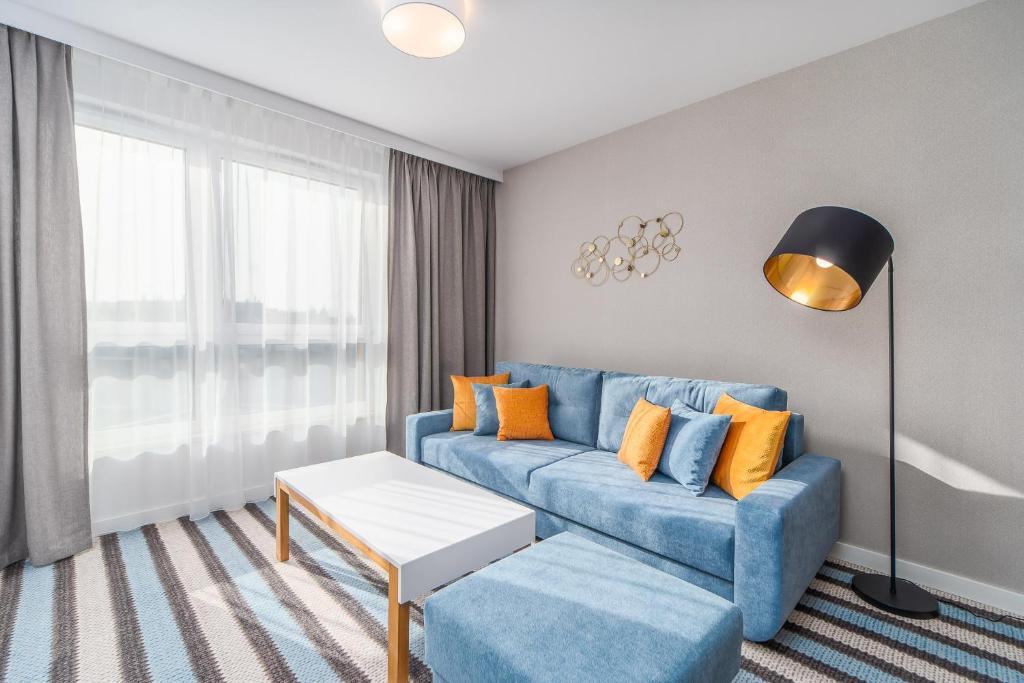 米兹多洛杰Sunny Apartments in Bel Mare Resort by Renters的客厅配有蓝色沙发和橙色枕头。