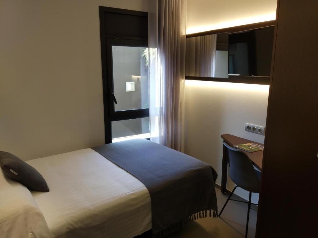 奥洛特Hotel Olot Centre的配有一张床、一张书桌和一扇窗户的酒店客房