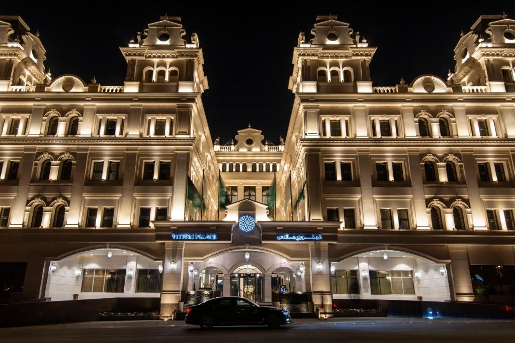 利雅德Vittori Palace Hotel and Residences的夜间停在大楼前的汽车