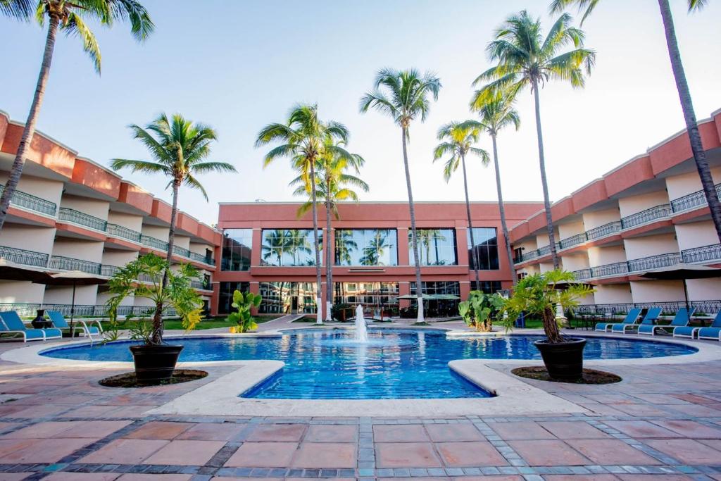 特皮克Nk Hotel Nekié Tepic的酒店庭院种有棕榈树,设有游泳池