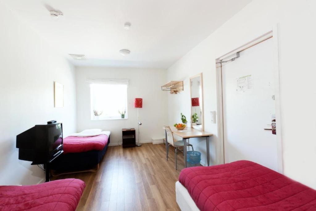 乌普萨拉Vandrarhem Kvarntorget的客房设有两张床、一台电视和一张桌子。