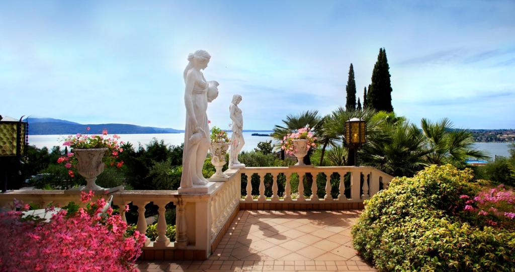 加尔多内-里维耶拉Park Hotel Ville Montefiori的花园,花园内有雕像,围栏上有鲜花