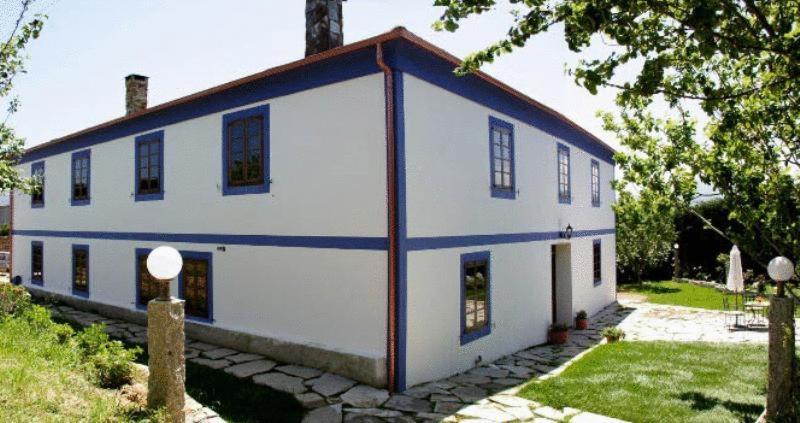 里瓦德奥Casa Rural Vila Pomar的白色的房子,有红色和蓝色的屋顶