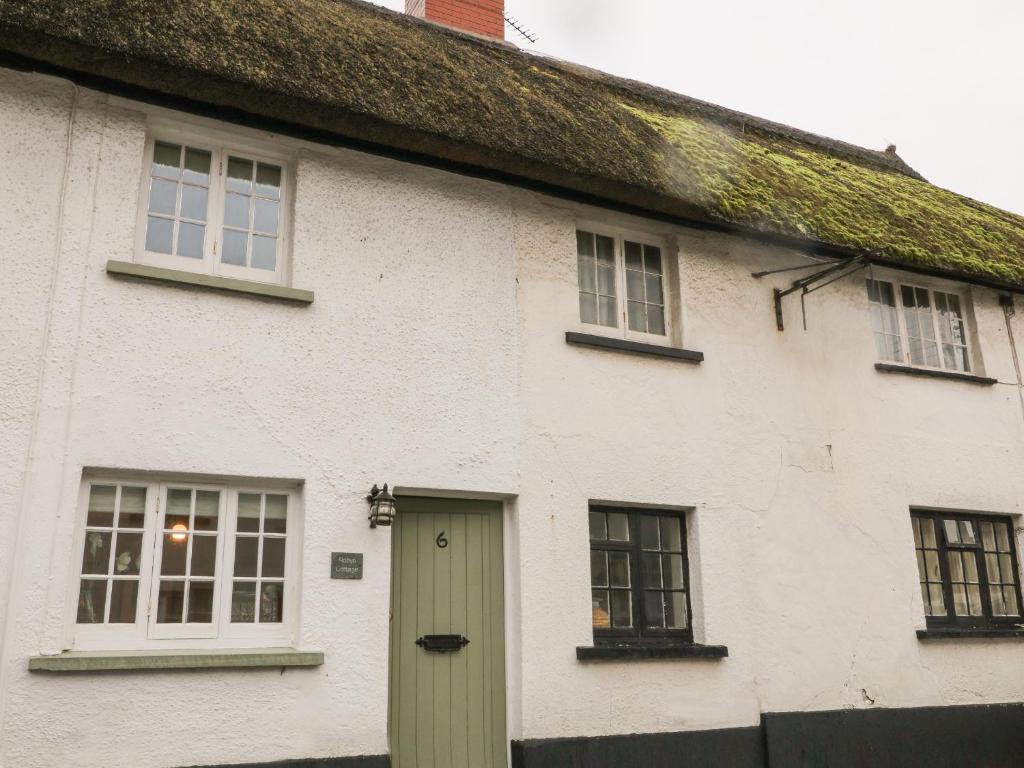 巴德利索尔特顿Robyn Cottage的白色的房子,设有绿色的门和窗户