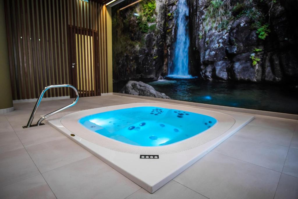 吉尔斯Hotel São Bento da Porta Aberta & Spa的一个带按摩浴缸的浴室,浴室内拥有瀑布壁画