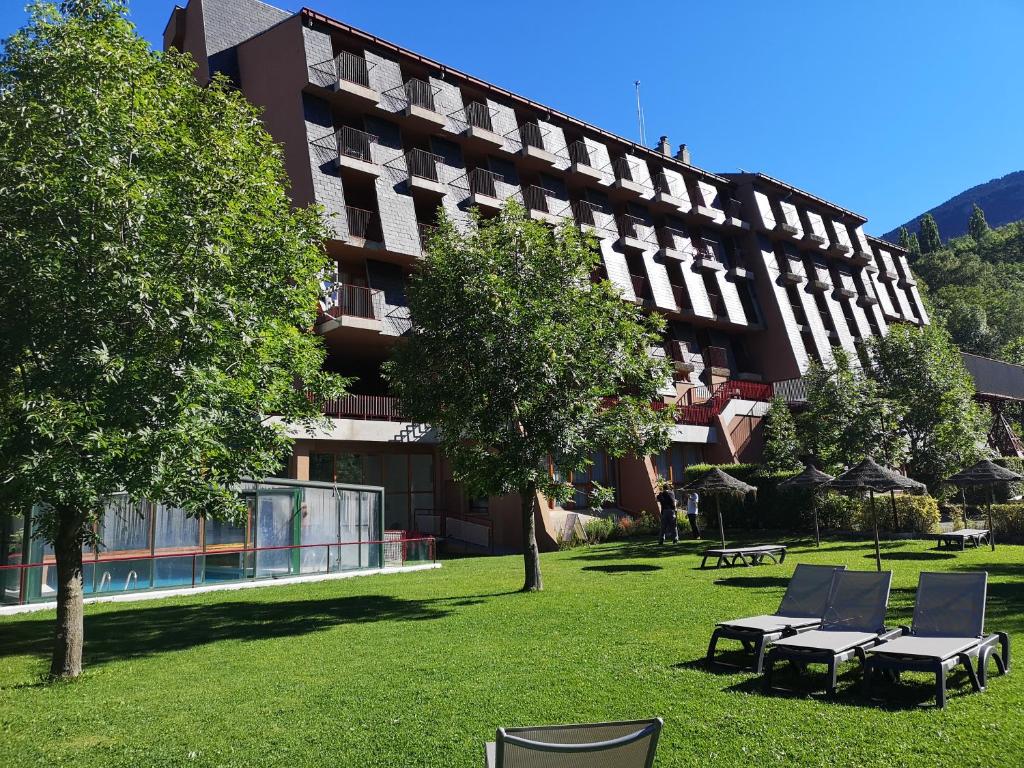 塞尔勒埃文尼亚蒙特阿尔巴酒店的一座大建筑,前面有椅子和树木