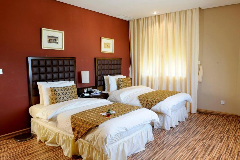 科威特Spice Hotel的红色墙壁的酒店客房内的两张床