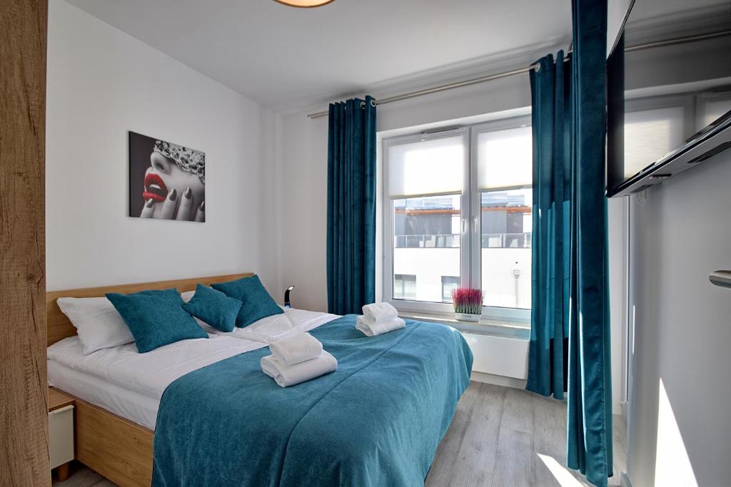 科沃布热格Apartament Nadmorskie Tarasy SPA Deluxe的一间卧室配有一张带蓝色床单的床和一扇窗户。