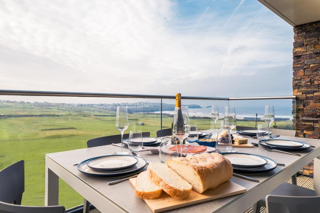 纽基Newquay Fistral Beach View的阳台上的桌子上摆放着面包和酒杯