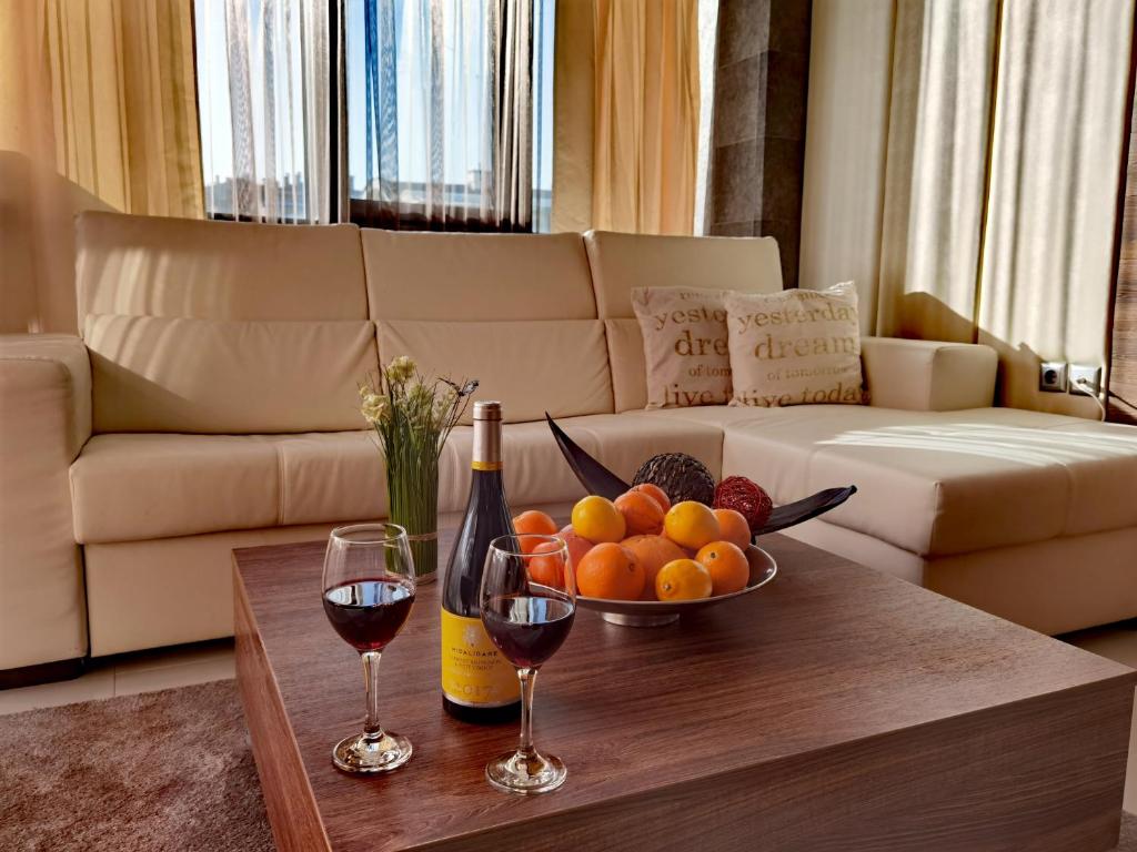 舒门阿克申酒店的一张桌子,上面放着一碗水果和两杯葡萄酒