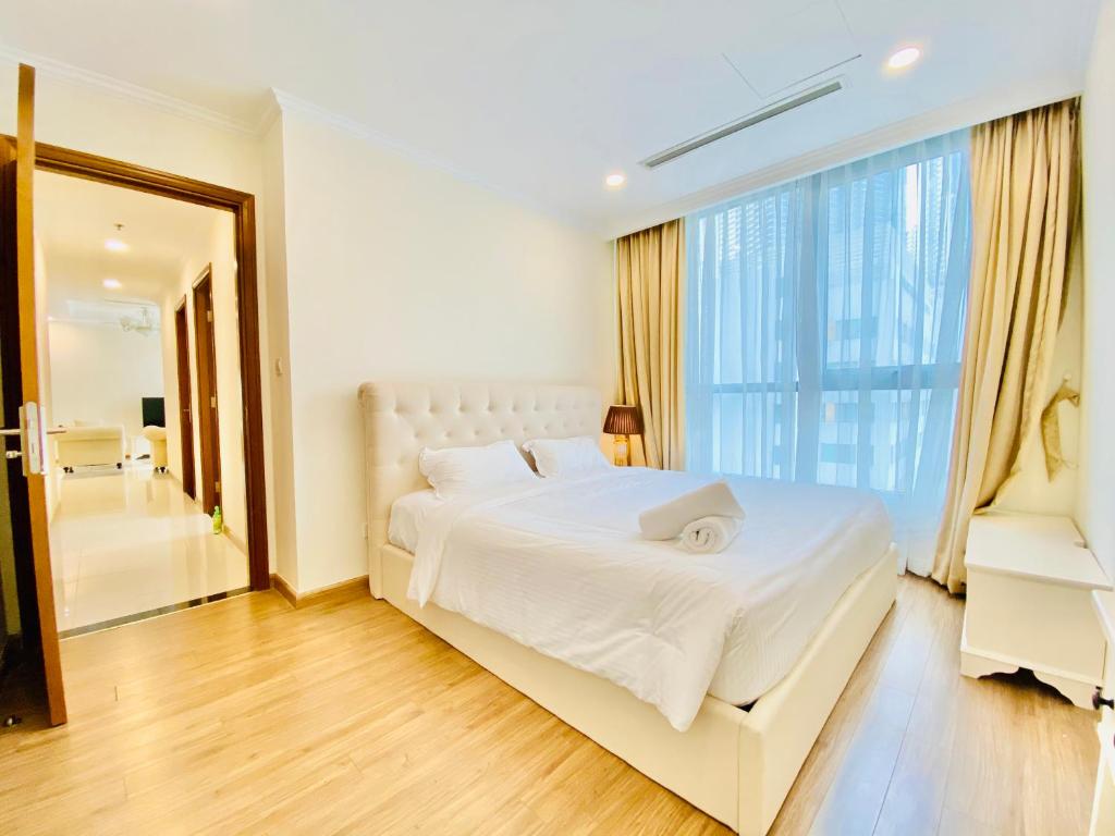 胡志明市The Landmark Vinhomes-Service Apartment的卧室设有白色的床和大窗户