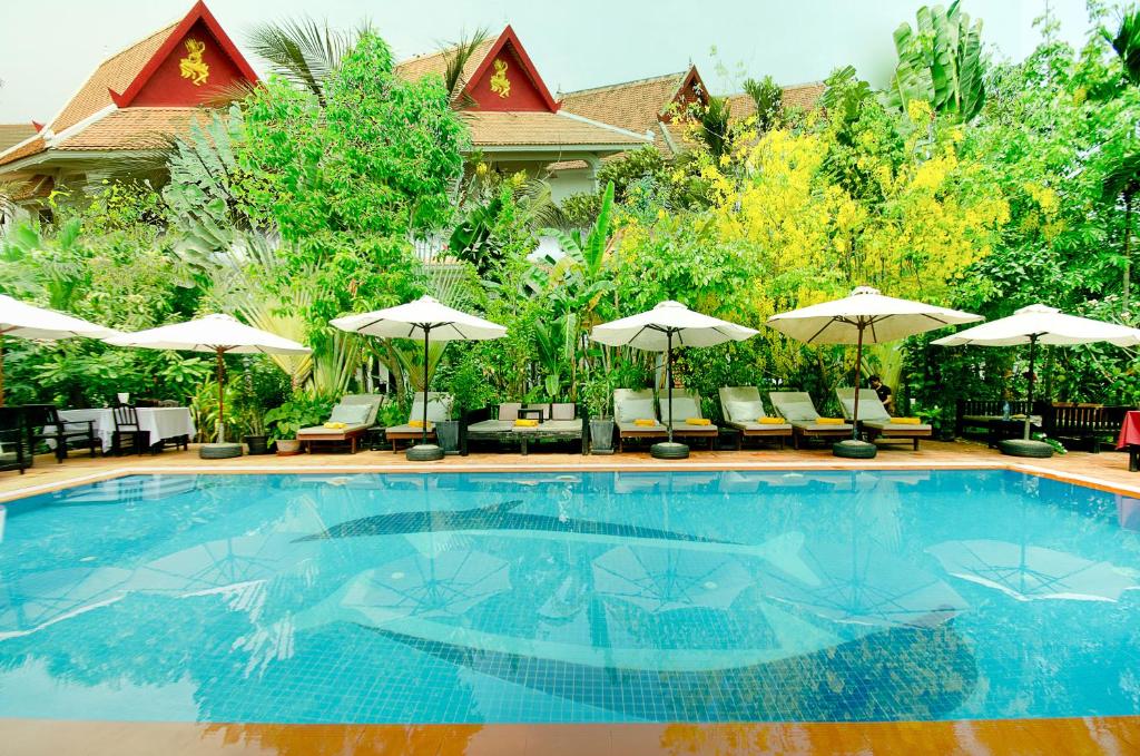 暹粒桑那龙精品度假村的一个带椅子和遮阳伞的游泳池
