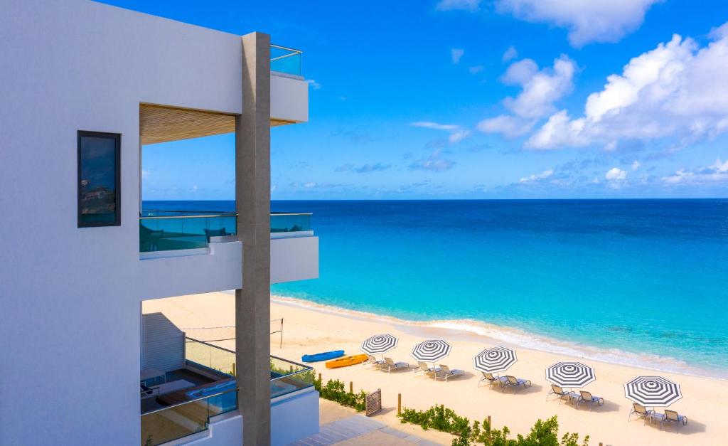 Meads BayTranquility Beach Anguilla Resort的享有带椅子和遮阳伞的海滩美景