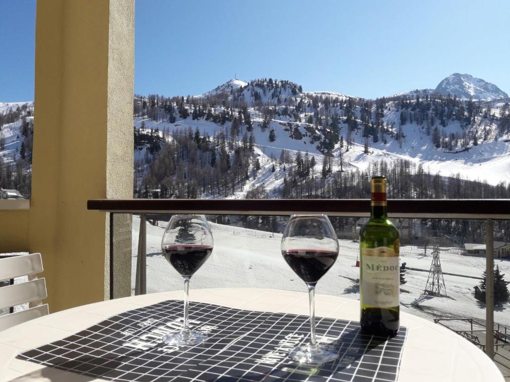 伊索拉2000Appartement 4/6 pers plein sud. Front de neige的两杯红酒坐在桌子上,窗户