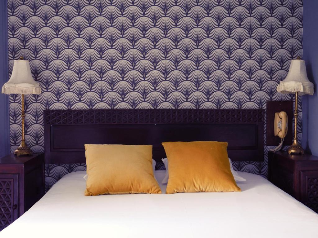 比亚里茨Saint Charles Hôtel & Coliving Biarritz的卧室配有一张带两个枕头的床和一堵墙