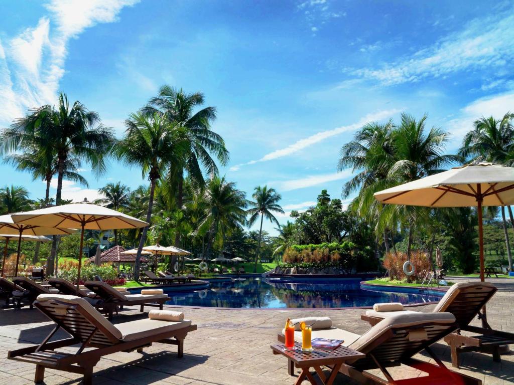 梳邦再也吉隆坡绍嘉纳度假村的度假村的游泳池,配有椅子和遮阳伞