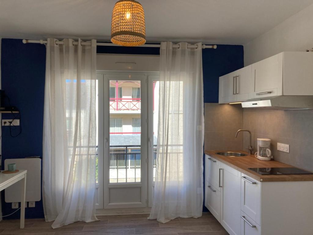 拉波勒La Capitane的厨房配有白色窗帘,门上设有窗户
