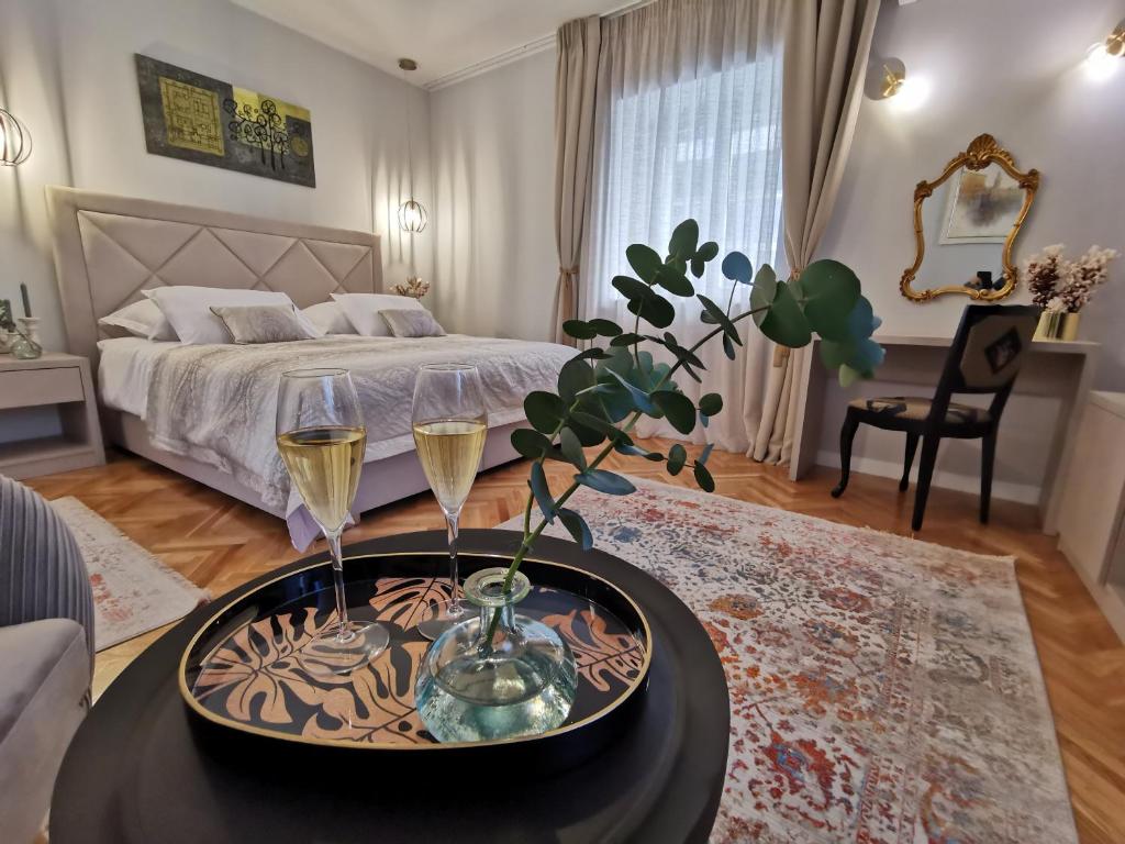斯普利特Merla Art & Luxury Rooms的一间卧室配有一张床和一张桌子,并配以两杯葡萄酒