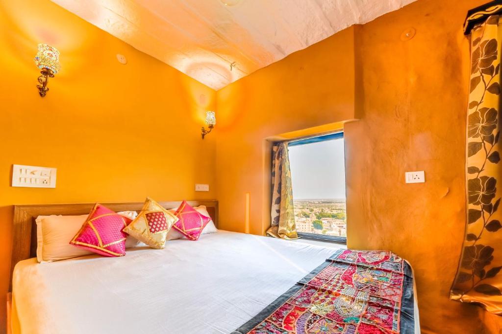 斋沙默尔泥镜旅馆的一间卧室设有橙色的墙壁和一张带色彩缤纷枕头的床。
