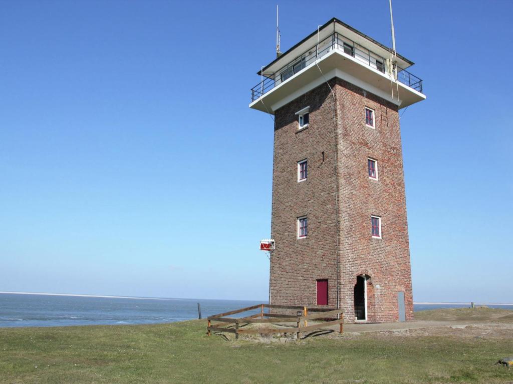 赫伊斯代嫩Heritage Holiday Home in Huisduinen near Sea的海滨砖砌灯塔