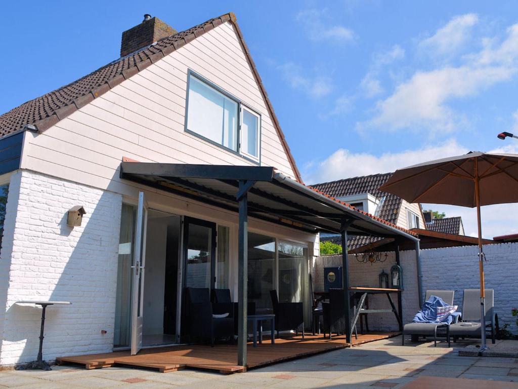 诺德克豪特Lovely Holiday Home in Noordwijkerhout near Lake的一座带庭院和遮阳伞的房子