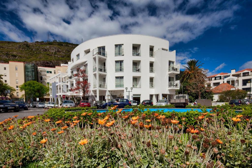 马希库白色水域酒店的一座白色的建筑,前面有一个花园