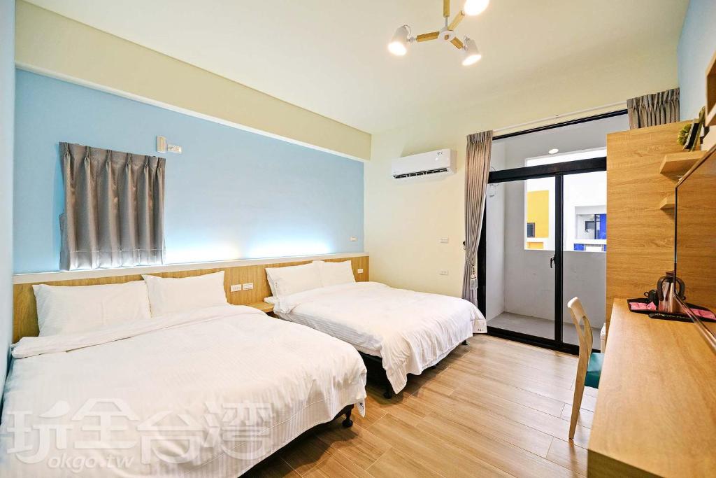 马公澎湖原慕心民宿的一间卧室设有两张床、一张桌子和一个窗口。