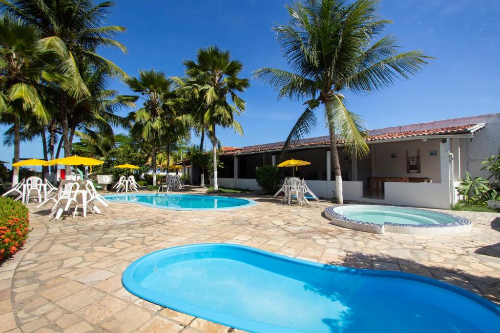 雅克南Pousada Do Inglês的度假村设有2个游泳池和椅子,并种植了棕榈树