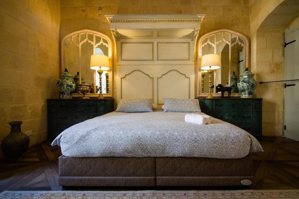 维洛里奥萨Palazzino Birgu Host Family Bed and Breakfast的一间卧室配有一张大床和两面镜子