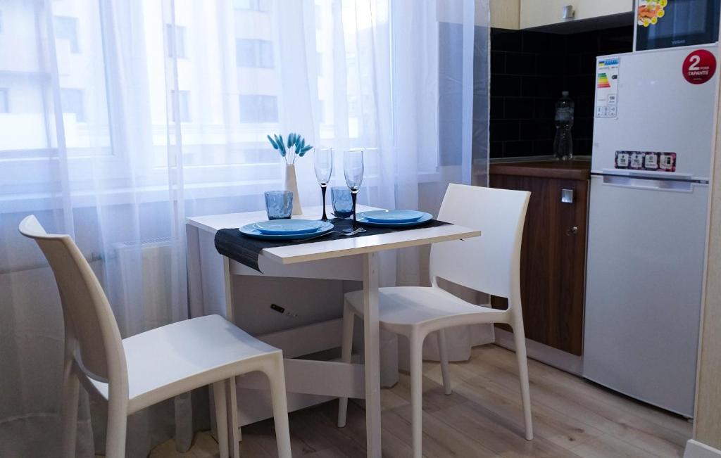 哈尔科夫Комфортная студия Вокзал Харьков-Пассажирский的小厨房配有桌椅和冰箱。