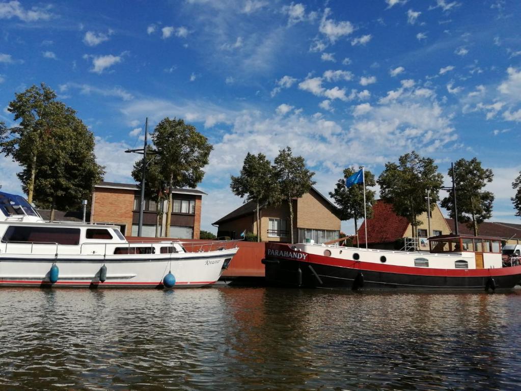 迪克斯梅德Vakantiehuis Bloemmolenkaai的两艘船停靠在房屋旁边的水中