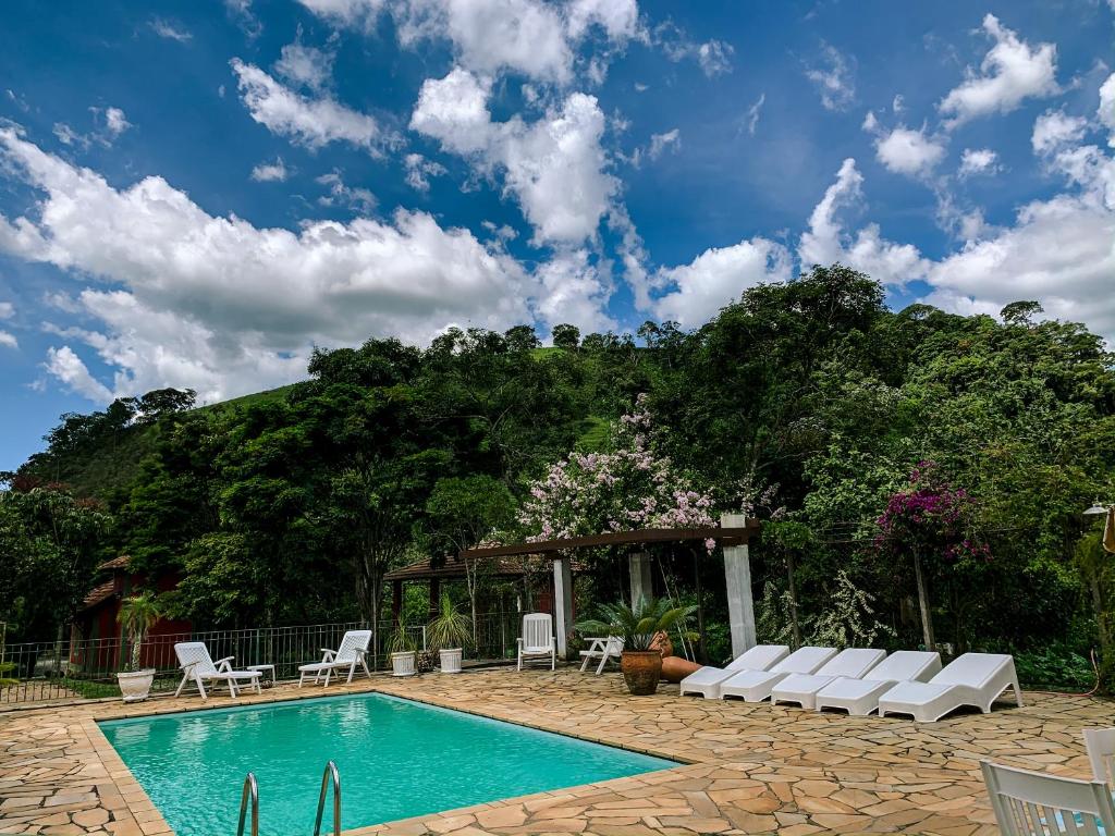 帕萨夸特鲁Pousada das Pedras的一个带白色椅子的游泳池和一个凉亭