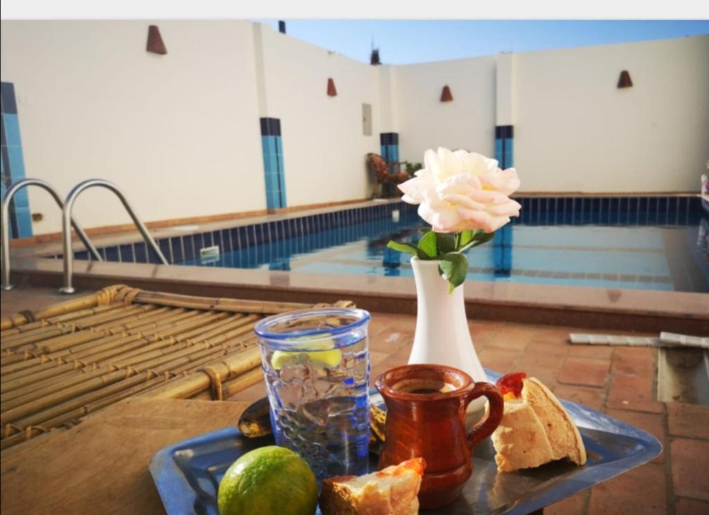 卢克索Sinderella Private Pool Villa的一张桌子,上面有玫瑰花,面包,花瓶,